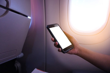 business man sits in airplane watching his cell phone