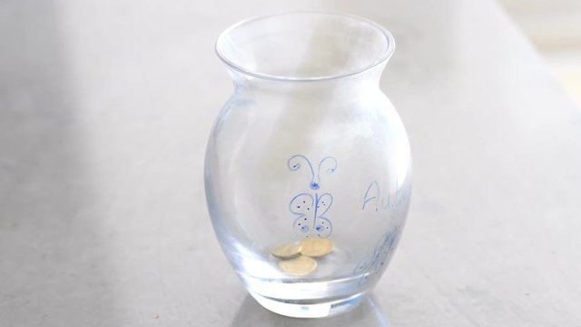 Dropping money into childs money jar