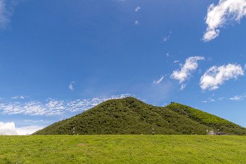 Green hills and fence lush grass, blue sky with white clouds