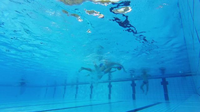 An underwater shot of two water polo players who are challenging for the ball.