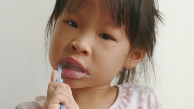 Young asian girl brushing her teeth in bathroom