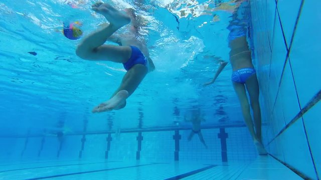 An underwater slow motion of a water polo player shooting the ball.