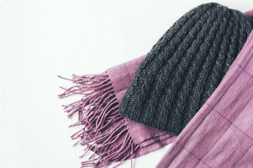 Gray woolen knitted hat and pink scarf on a white background