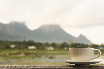 white cup on wooden table with lake view