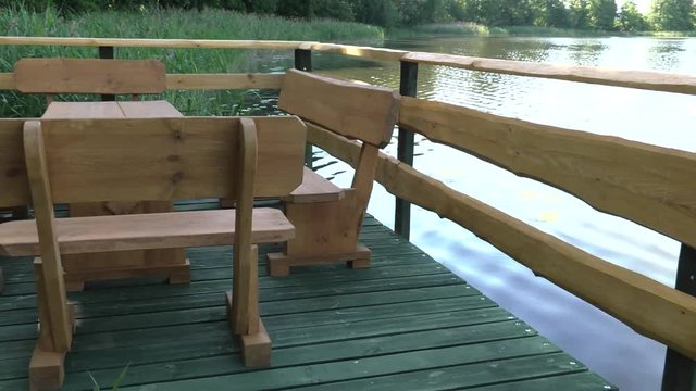 Wooden chairs and one table. The platform above water. Lake. Rushes. A place of rest and relaxation. 