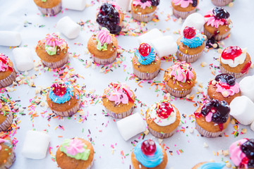 Many tasty colorful cupcakes on white background