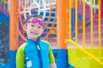 Little asian girl playing and smiles in water park