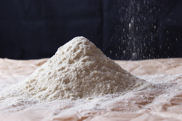 Handful of flour with flaky flour on a dark background.