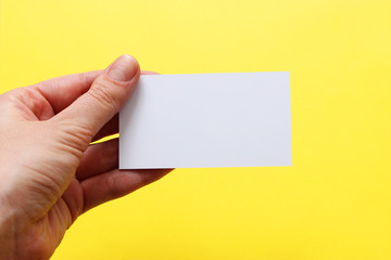 White business cards in woman hand  on a yellow background.