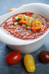 Close-up of tomato soup gazpacho served in a white bowl, vertical shot
