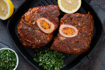 Raw marinated cross cut veal shank for making ossobuco on a cast-iron grill, view from above, closeup