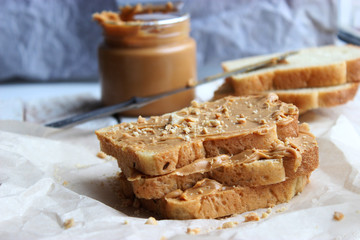 toasted white bread smeared peanut butter on a white plate on a light background