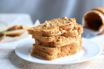 toasted white bread smeared peanut butter on a white plate on a light background