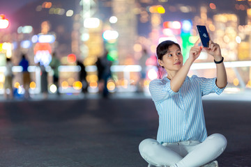 Woman using smartphone at night with Victoria Horbor in background