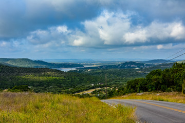 Open Road in the hill country underneath clouds and open sky.