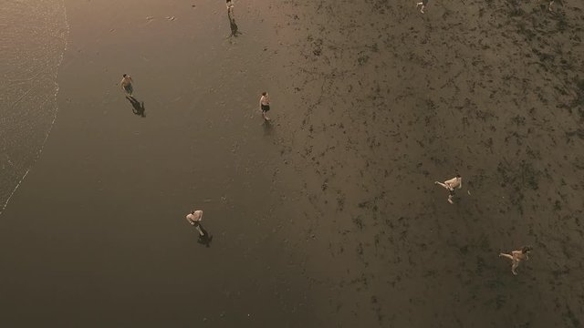 Men playing soccer on the beach at sunset, Dramatic Aerial Pull