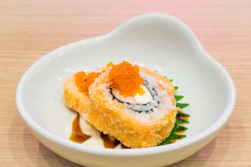 Bowl of Crispy Deep Fried Roll Sushi topped with small fish eggs. It is a new modern Japanese meal and delicacy.