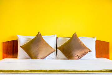 Interior decoration of romantic plain yellow bedroom. It consists of bed, white pillows and gold...