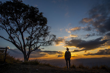 Silhouette of the Young woman looking at sunset on top mountain