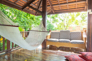 Chair and cradle in the Thai wooden house with sunlight flare, relax concept, Thailand