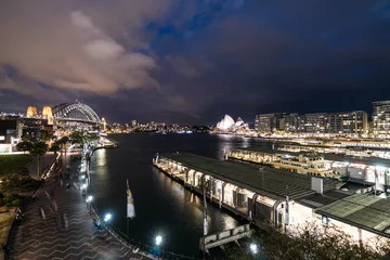 Deurstickers Stunning night view captured with blurred motion of the Circular Quay ferry terminal, the Sydney harbor bridge and the Opera house in Sydney, Australia largest city. © jakartatravel