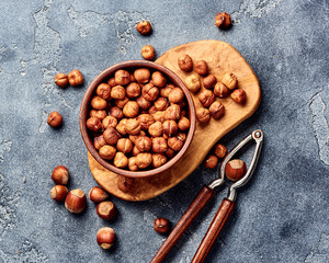 Hazelnuts with nutcracker on gray background. Top view of nuts.