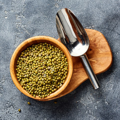 Green mung beans in wooden bowl on gray background. Top view of groats.
