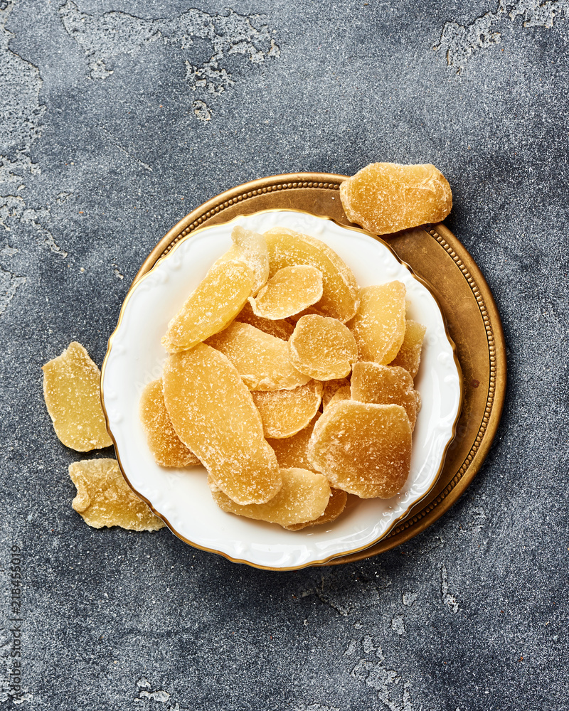 Wall mural Dried sweet ginger with sugar on a gray table. Top view.