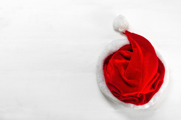 Bright red Santa Claus hat on wooden background.