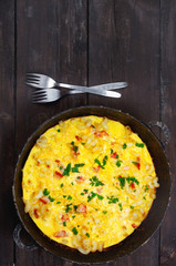 Traditional rustic omelette with bacon, pasta and greens