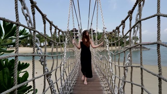 Lifestyle footage of Asian Chinese woman walking across rope bridge 