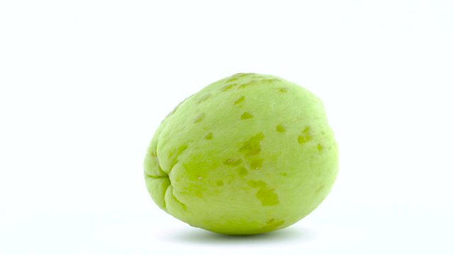One whole chayote fruit. Rotating on the turntable. Isolated on the white background. Close-up. Macro.
