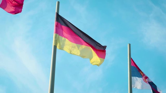 Flag of Germany waving in the wind in front of blue sky.