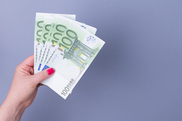 Female hand with a fan of euros on a blue background. Copy spase.