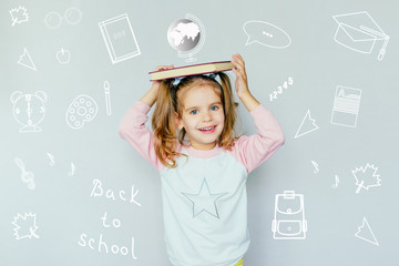 back to school. funny little girl from elementary school keeps a book on her head. education. child with book. selective focus. concept of education. the symbolism of the school.