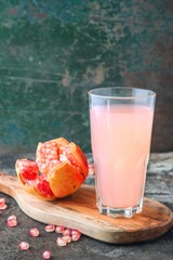 Ripe pomegranate with glass of pomegranate juice on rustic background