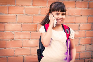 girl with backpack and books with her mobile phone