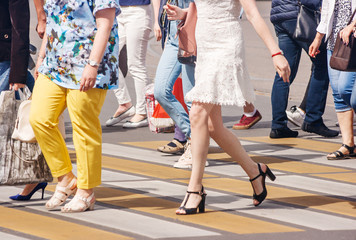 Fototapeta na wymiar legs of pedestrians in a crosswalk on summer day