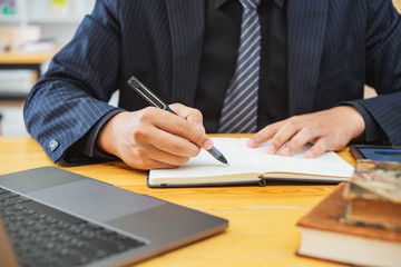 Male hand with pen writing in notebook on desktop