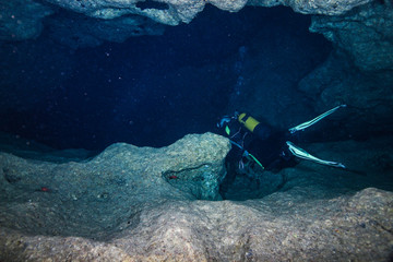 A scuba diver enters an underwater cave