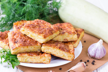 Pie with zucchini, cheese and herbs on the table