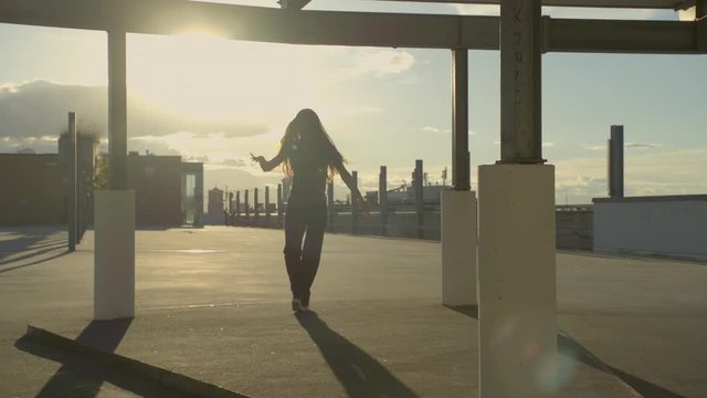 girl dancing urban style in sunset in an urban scenery