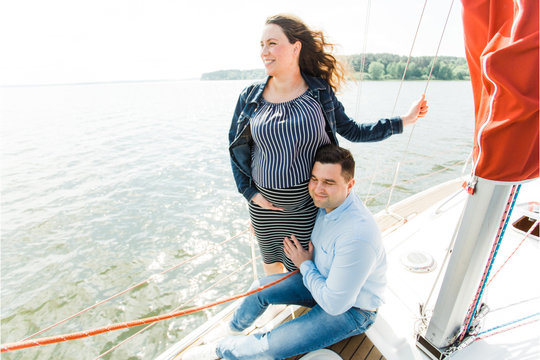 Pregnant woman with husband on yacht. Happy pregnancy concept. Young family on vacation.