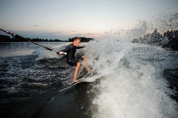 Active wakesurfer riding on blue river waves with splashes