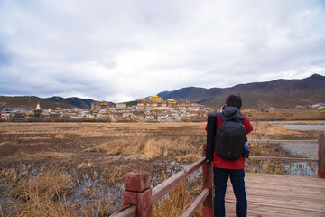 Fototapeta na wymiar Tourist man shooting beautiful landscape view of Songzanlin monastery golden temple land mark in Shangri-La city, China