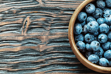 Blueberries in round wooden bowl on wood board copy space