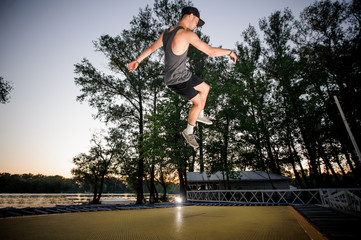 Active young man dressed in casual clothing trampolining in a park