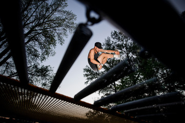 Bottom view of a young man trampolining in a park
