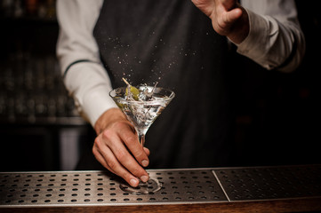 Barman making a fresh and strong summer martini cocktail with olive