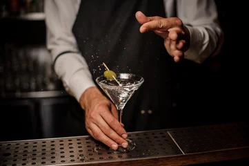 Zelfklevend Fotobehang Bartender making a fresh and strong summer martini cocktail with olive and salt © fesenko